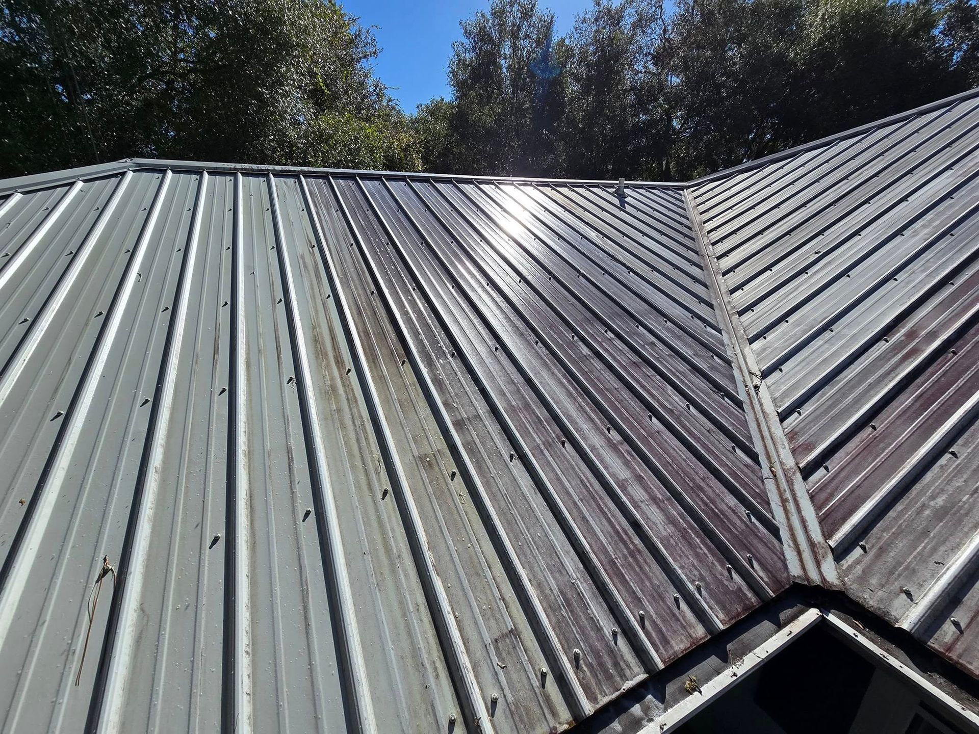 A close up of a metal roof with trees in the background
