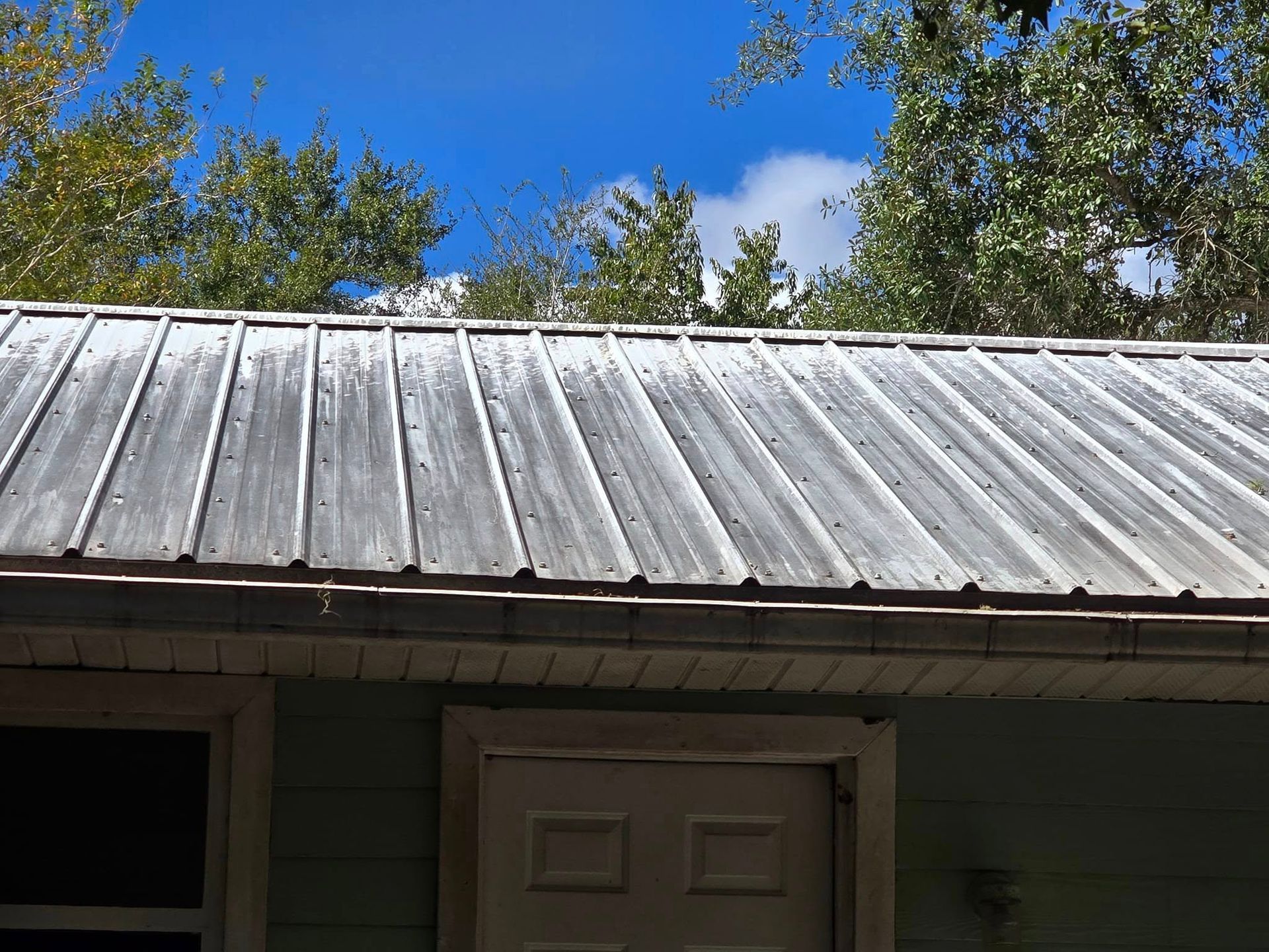 A metal roof on a house with a blue sky in the background.