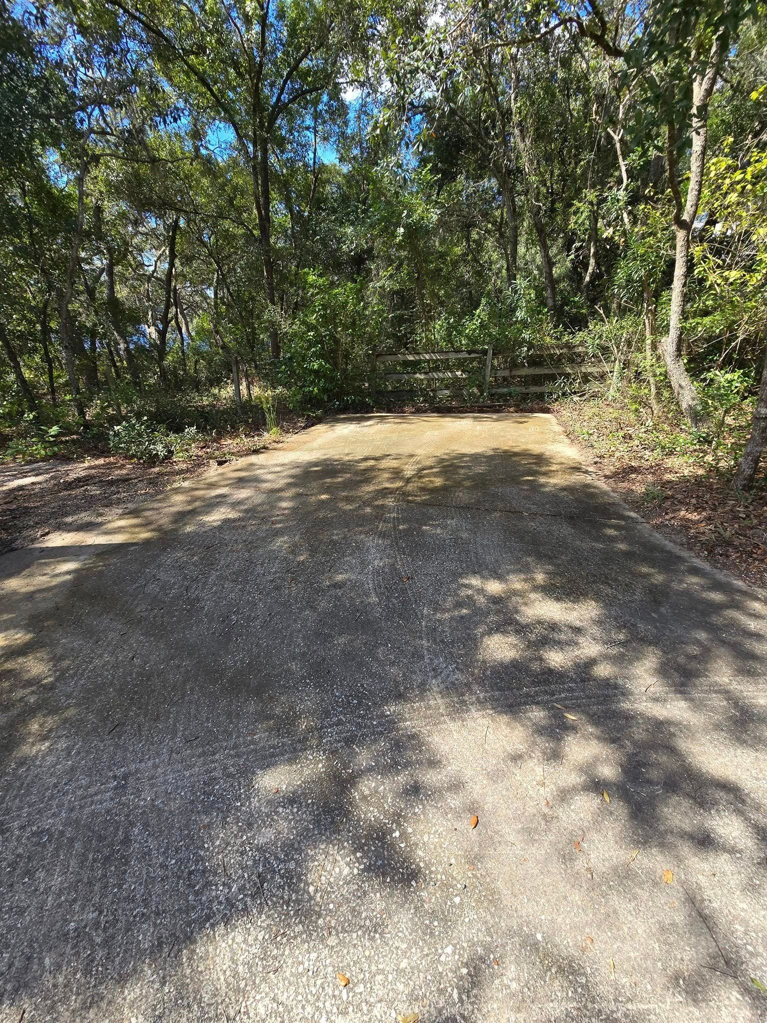 A gravel road going through a forest with trees on both sides.