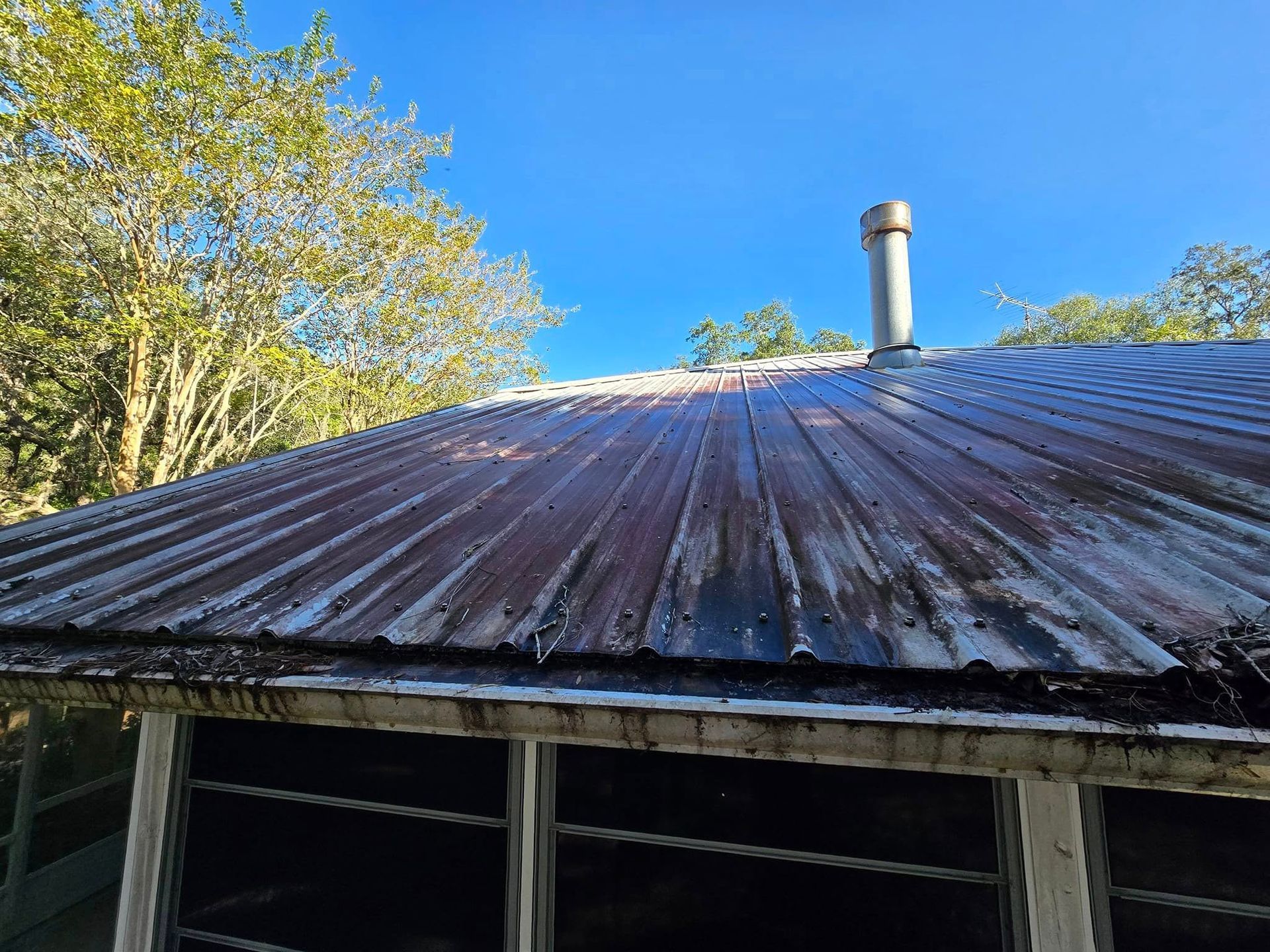 A rusty metal roof with a chimney on top of it.