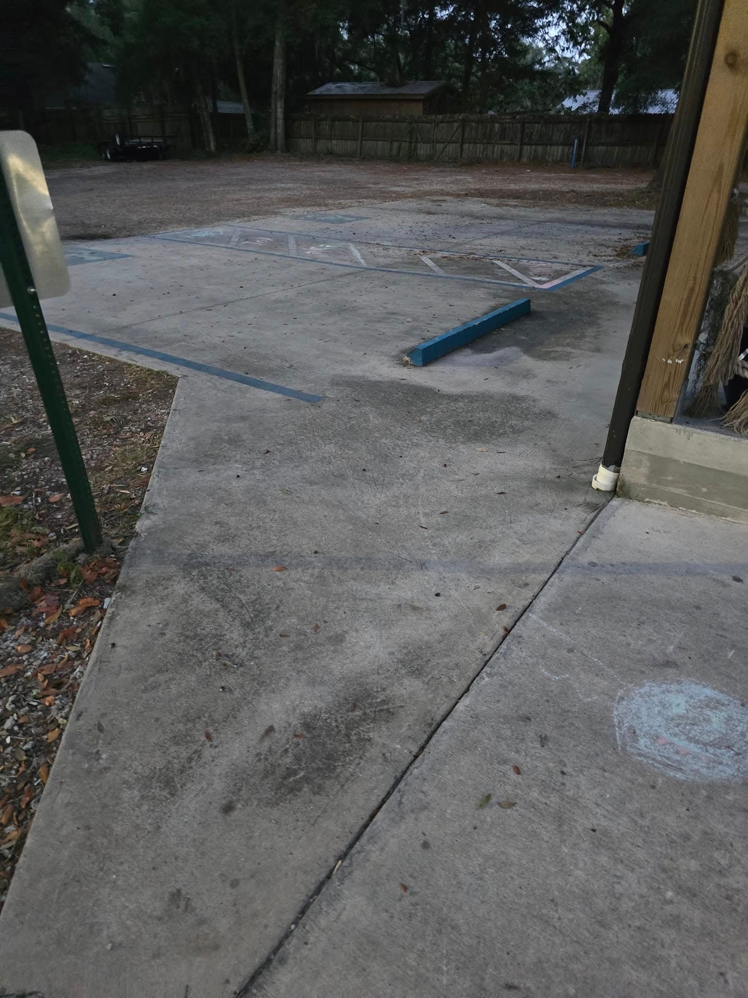 A concrete sidewalk next to a parking lot with a blue curb.