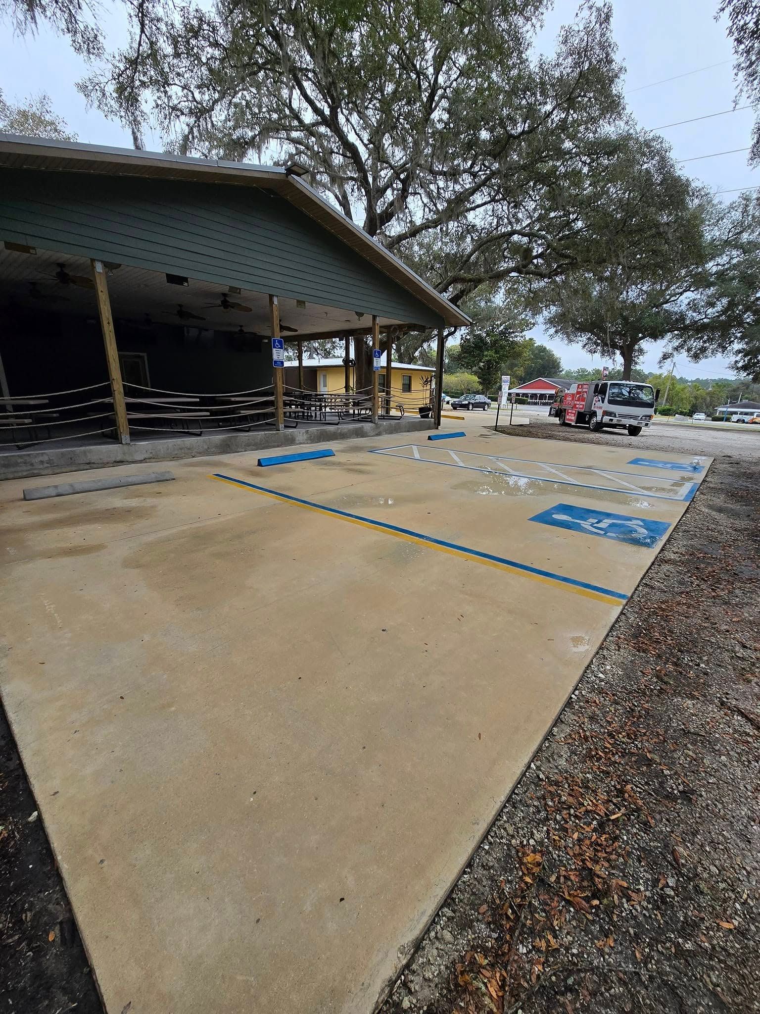 A parking lot with a handicapped parking spot and a pavilion in the background.