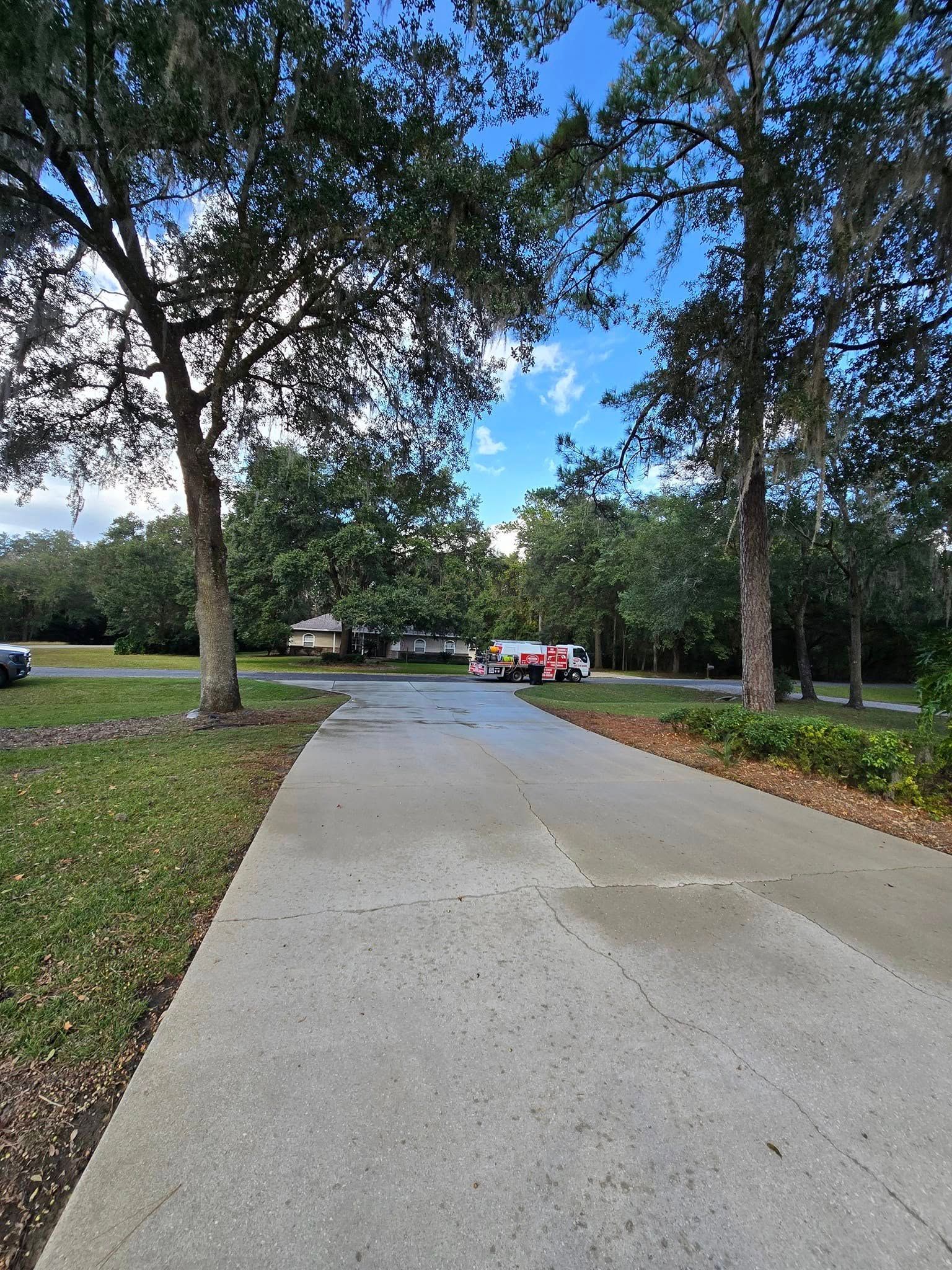 A concrete walkway leading to a parking lot surrounded by trees.