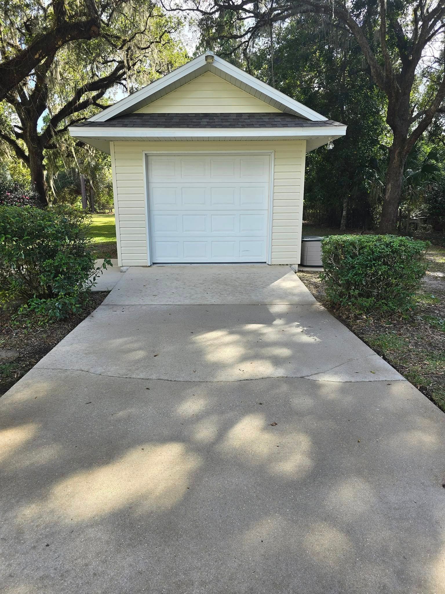 A small white garage with a concrete driveway leading to it.