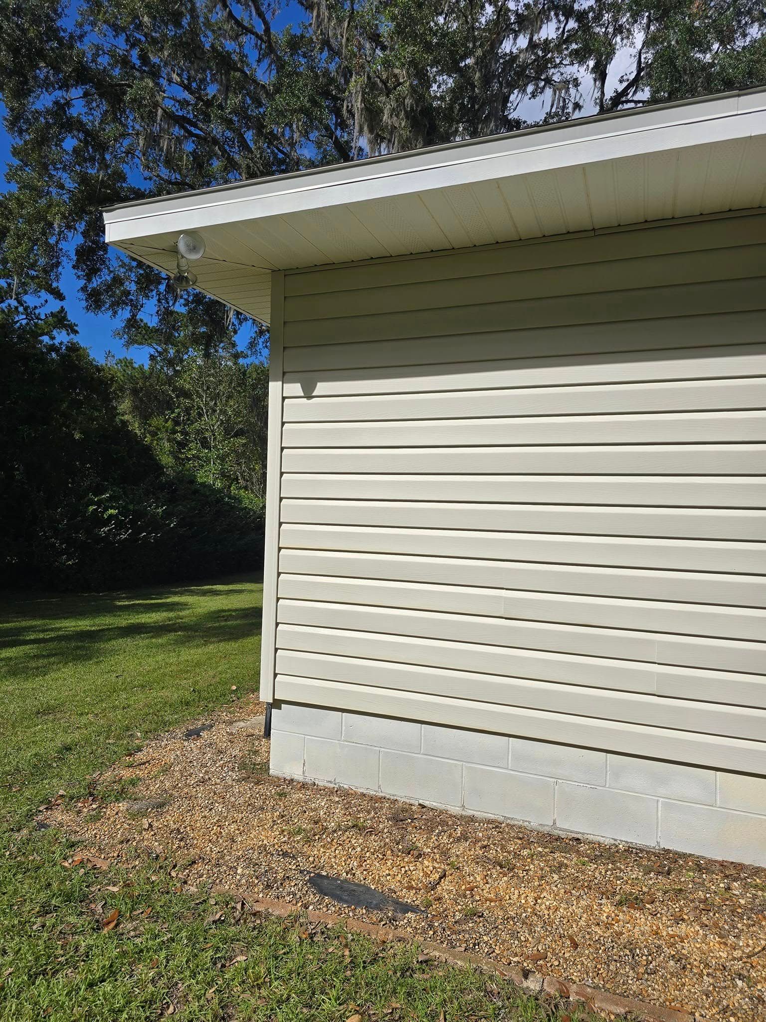A white house with a roof is sitting on top of a lush green field.