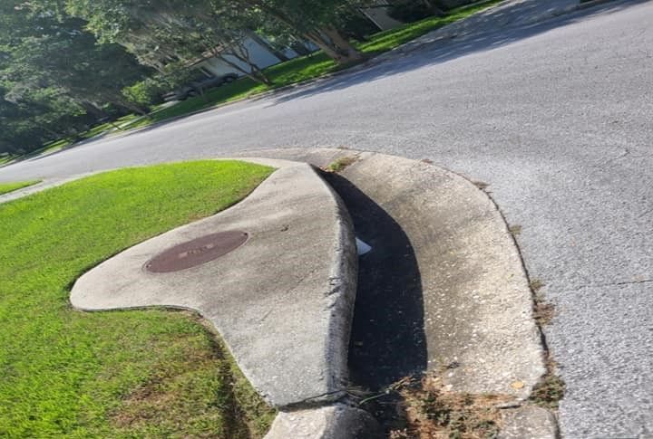 A curb on the side of a road with a manhole cover on it.