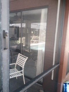 A chair is sitting on a screened in porch next to a sliding glass door.