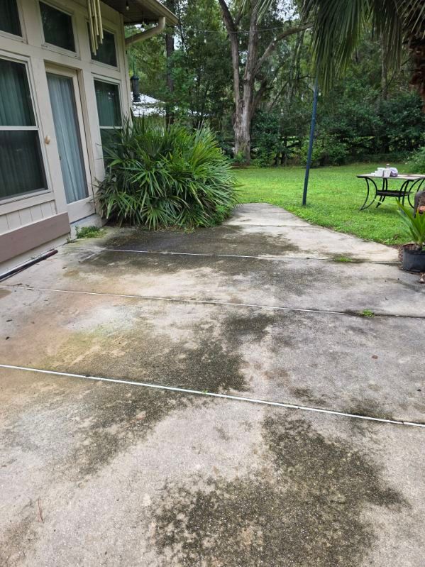 A white house with a garage and a driveway in front of it surrounded by trees.