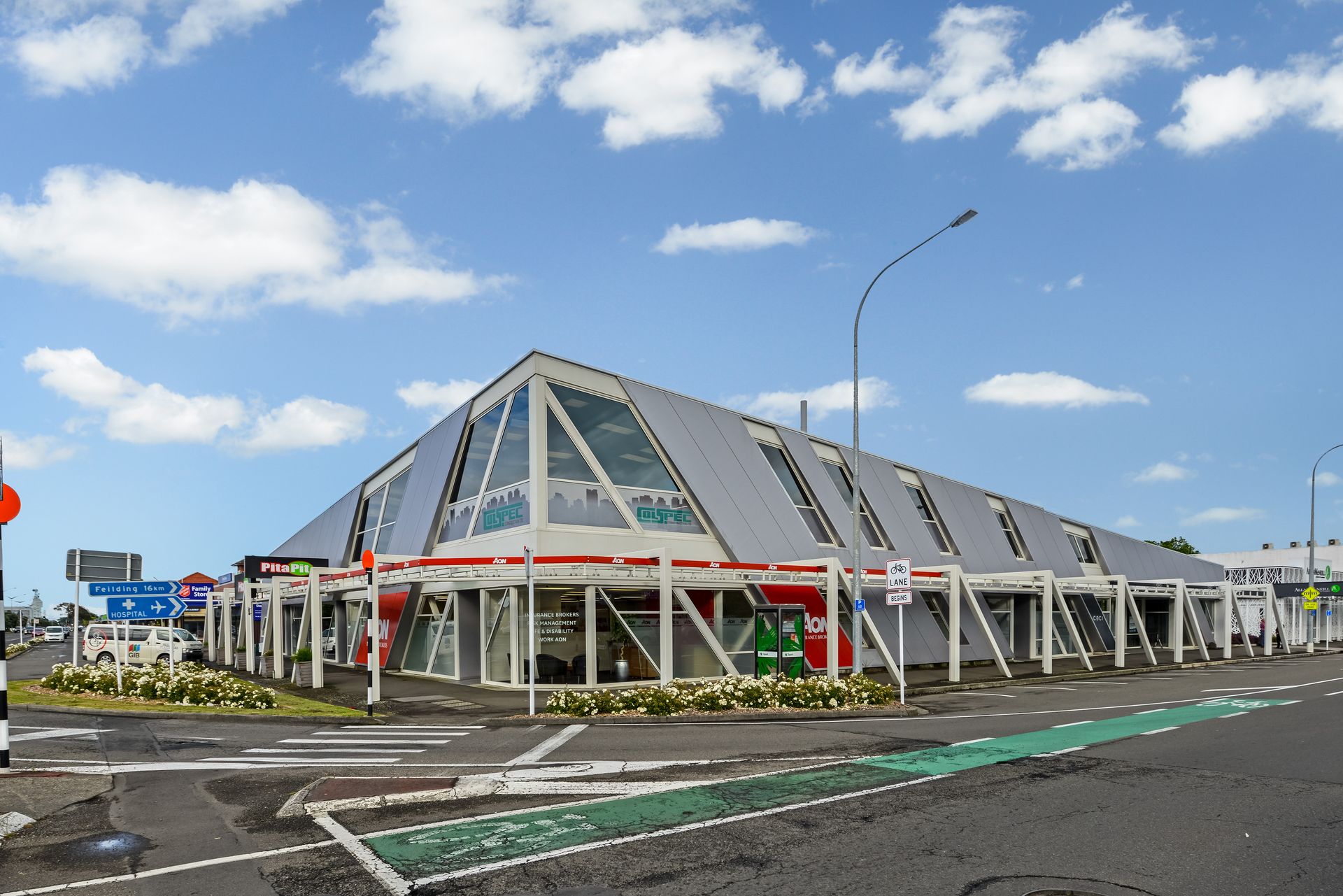 A large building with a lot of windows is on the corner of a street.