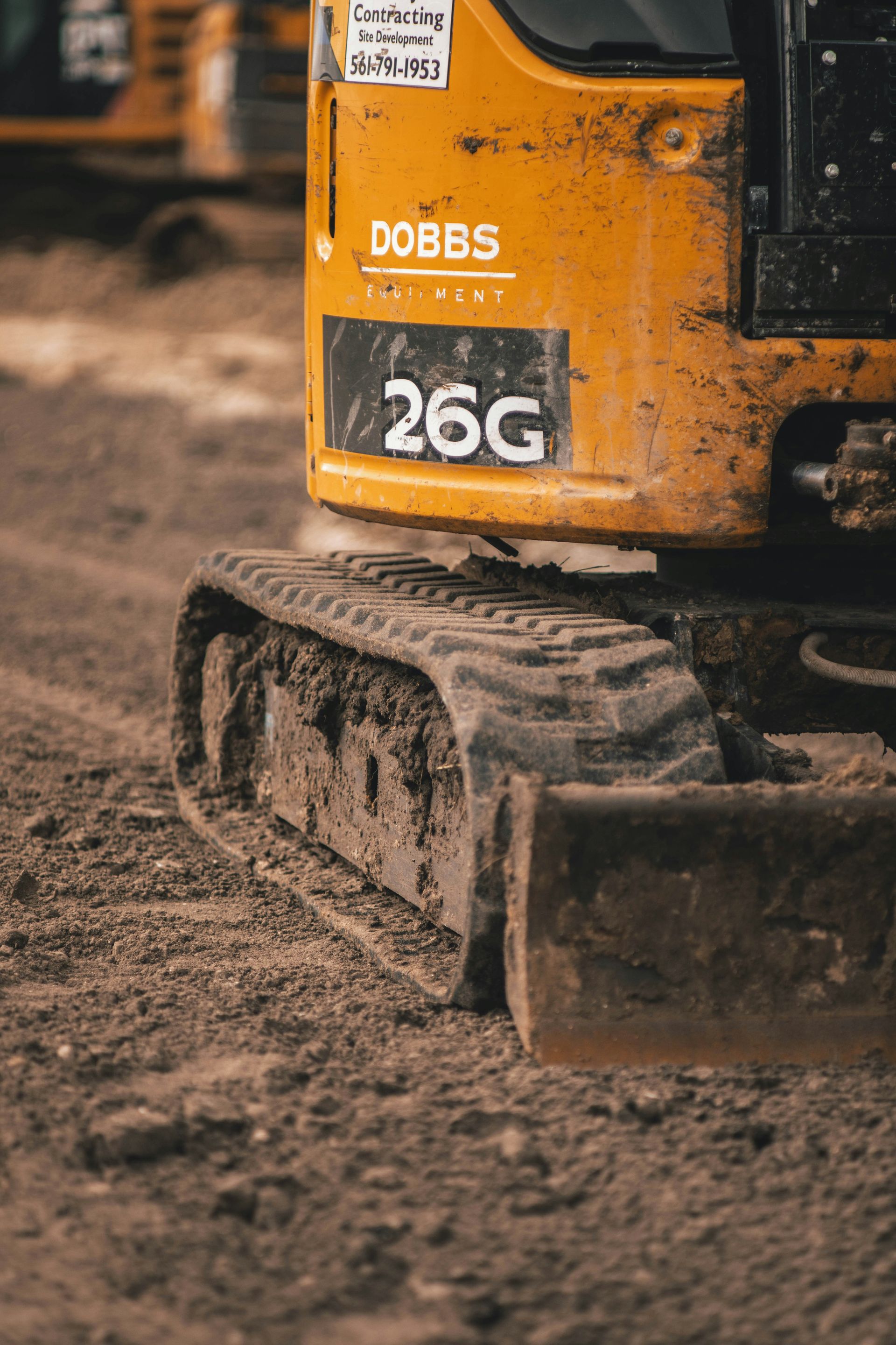 A close up of a yellow excavator on a dirt road.