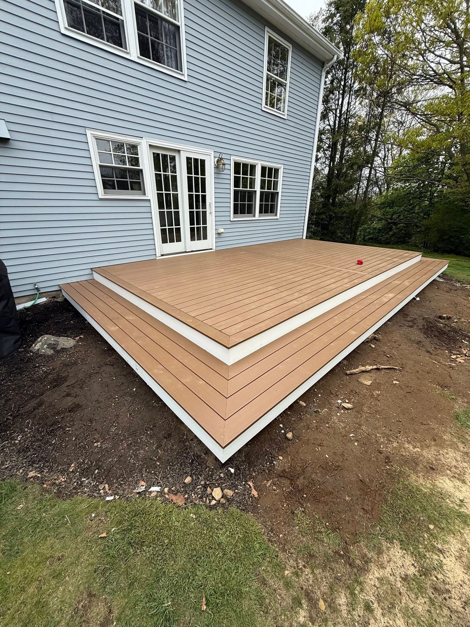 Completed composite deck with wraparound corner steps and white PVC fascia in Marbhead, MA