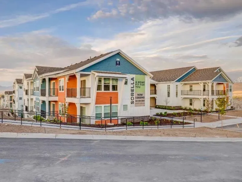 Exterior view of colorful apartment buildings with balconies and a fenced walkway.