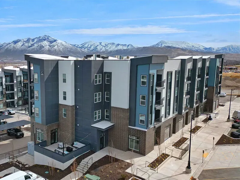 Exterior view of a modern apartment building with mountains in the background.