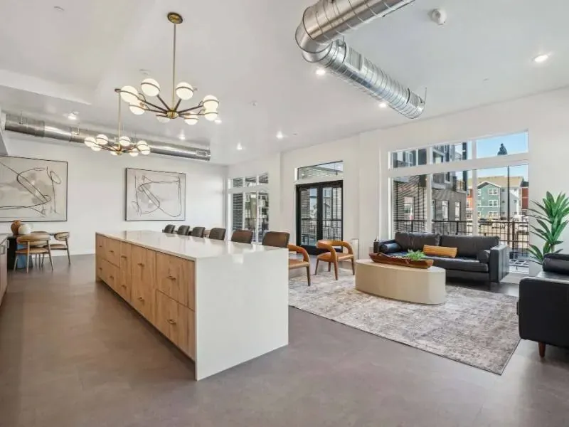 Bright communal lounge with a long white island, seating, and large windows.