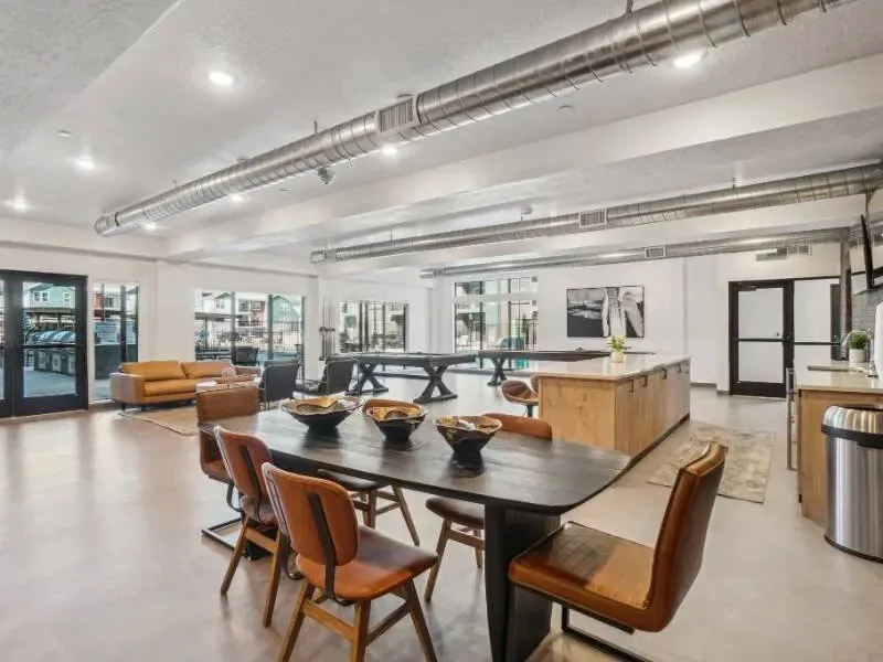 Spacious resident lounge with a long dining table and a modern kitchen area.