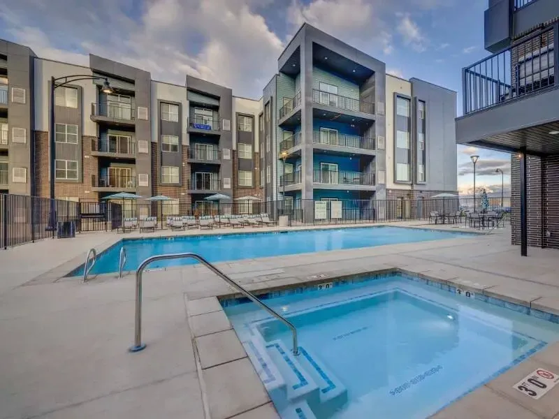 Outdoor community pool with a hot tub at a modern apartment complex.