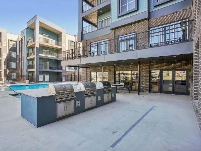 Outdoor community pool area with built-in grills and seating.