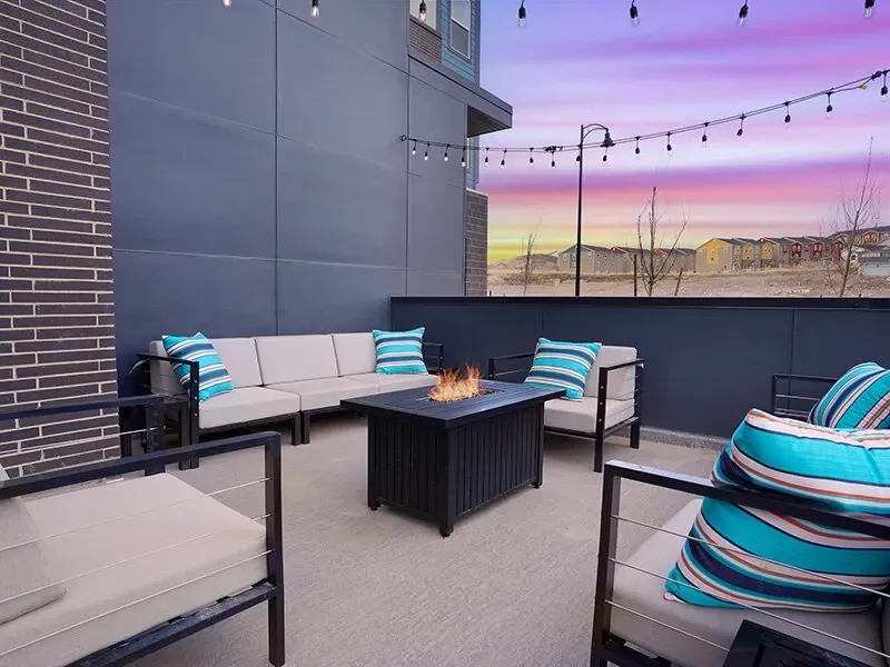 Rooftop community lounge with seating and a fire pit under string lights.