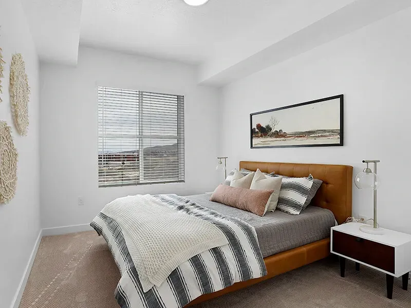 Bedroom in a modern apartment with a bed, two nightstands, and a window.