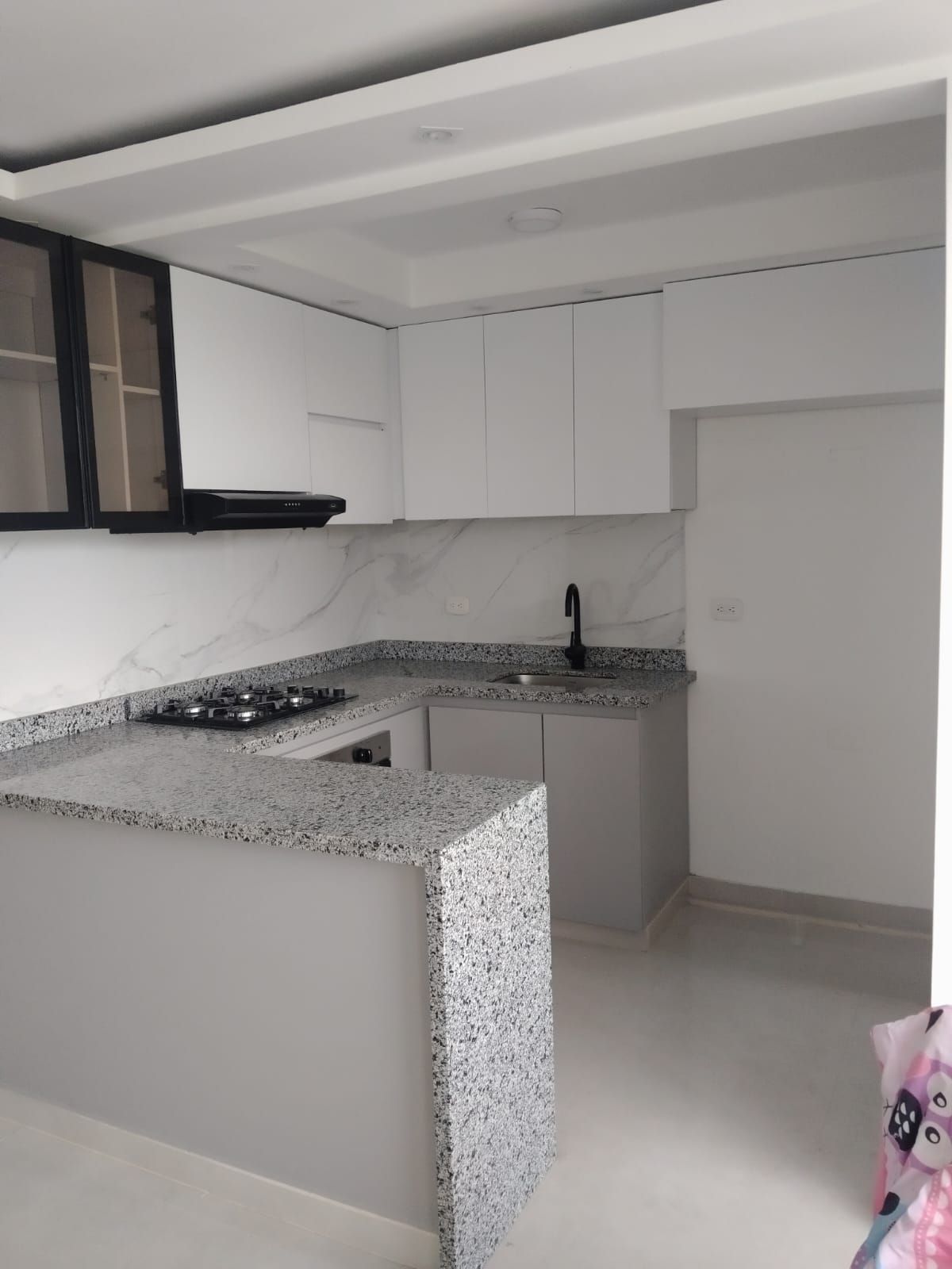 Cocina moderna gris y blanca con encimeras, gabinetes y electrodomésticos.
