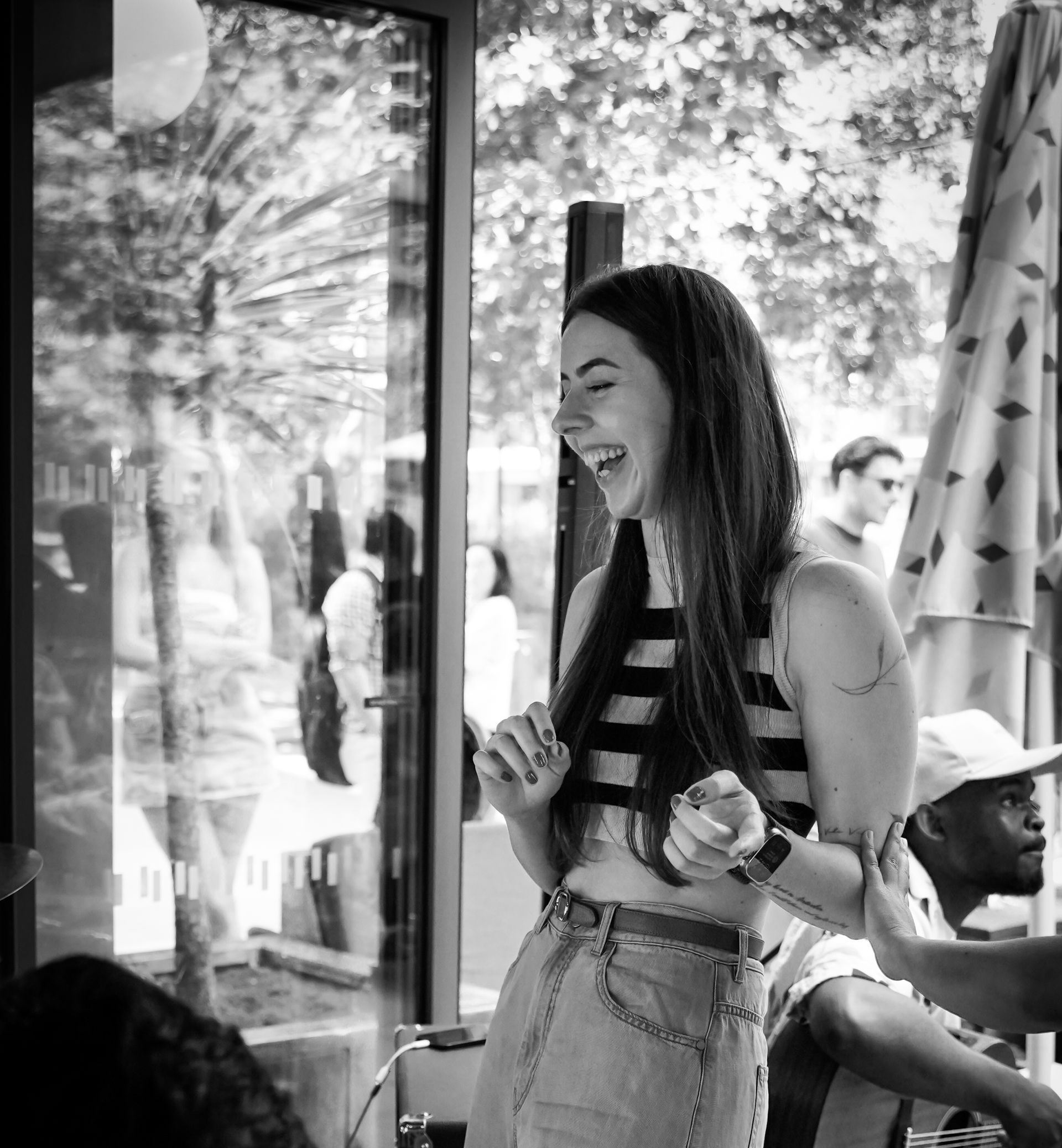 A black and white photo of a woman laughing in a restaurant.