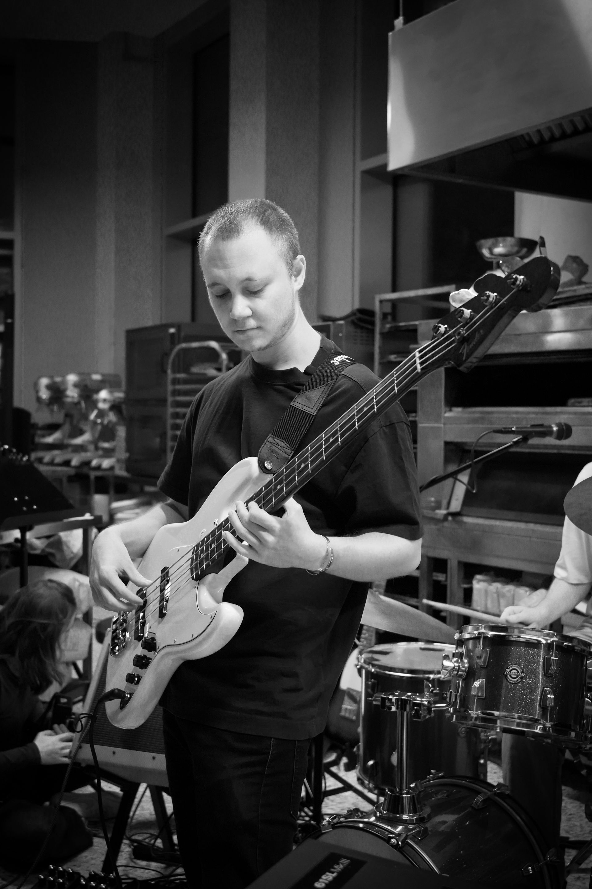 Man playing bass guitar in a studio. Black and white, stage lights.