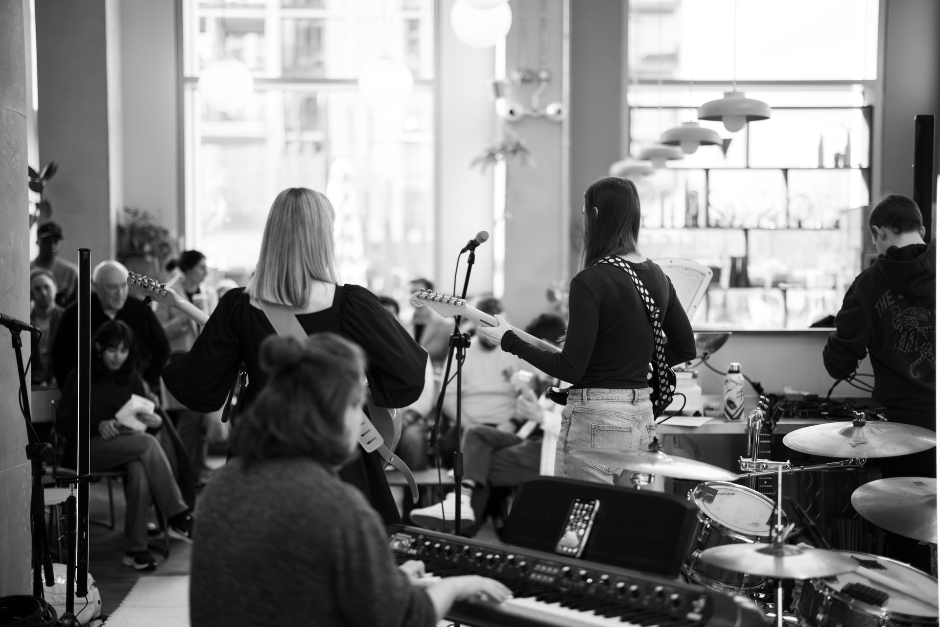 A black and white photo of a group of people playing instruments in a room.
