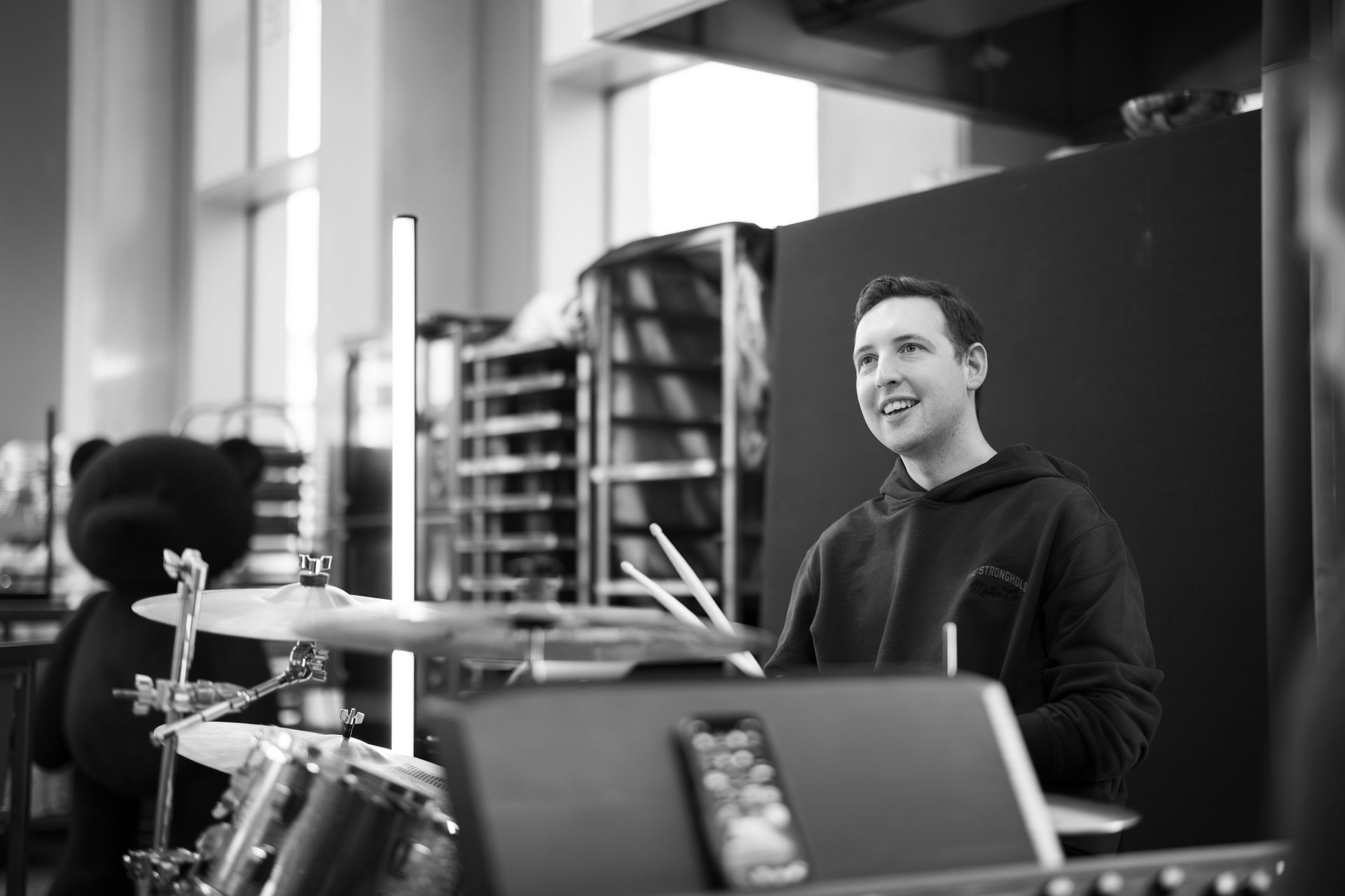 A man is playing drums in a black and white photo.