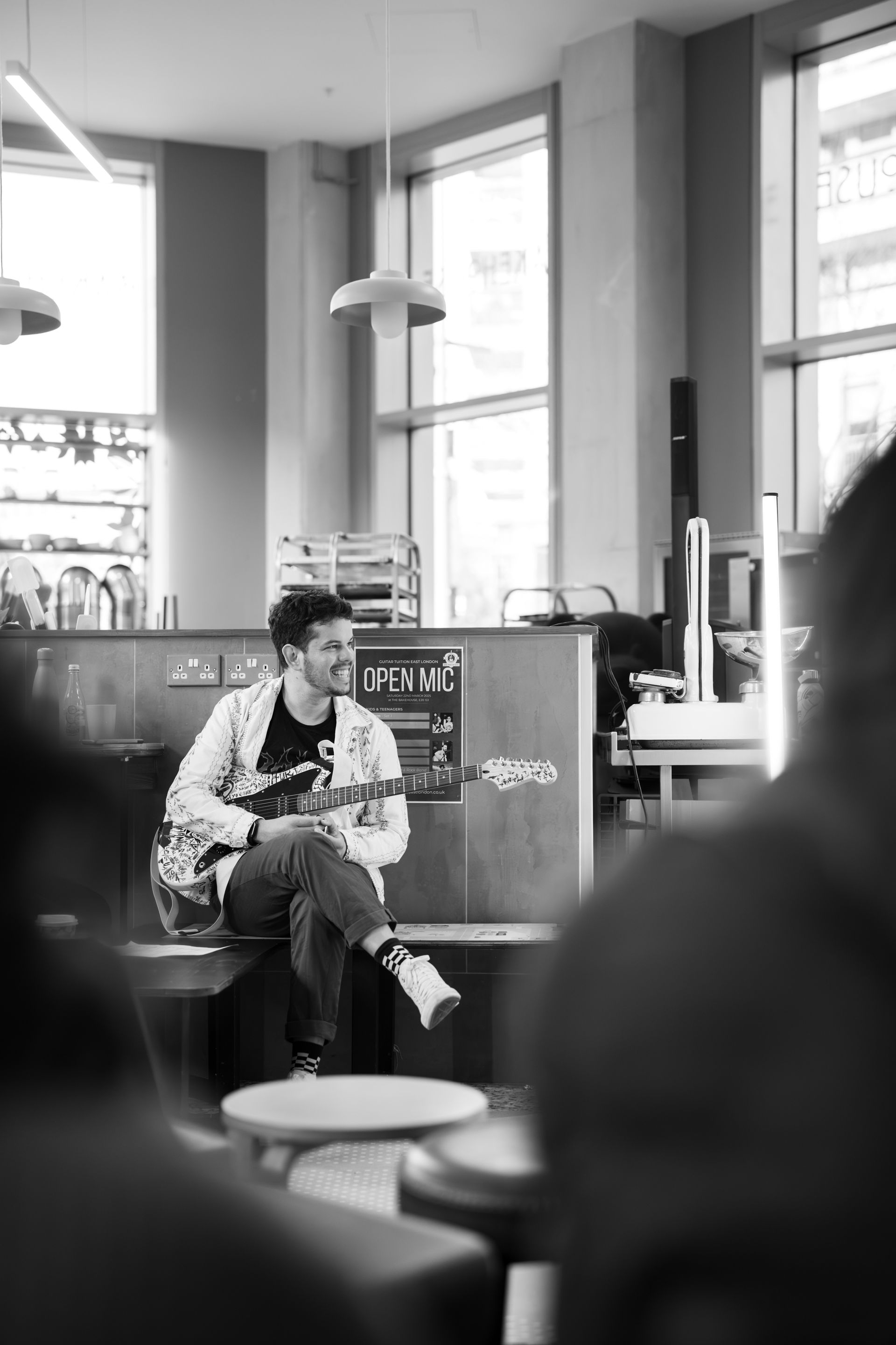 A man is sitting at a table in a restaurant playing a guitar.