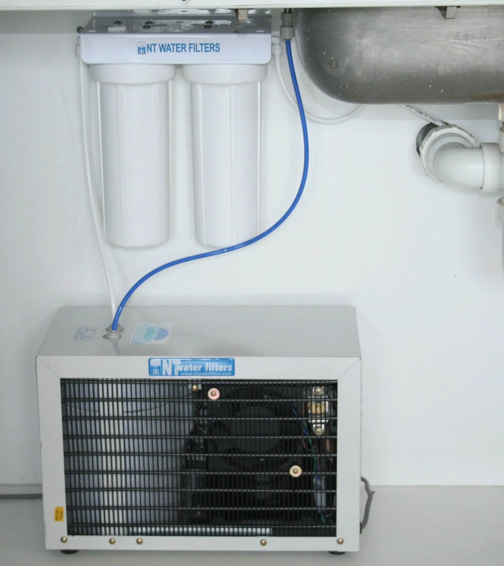 Water filter and ice machine under a sink, with white filters, blue tubing, and a white, vented machine. — NT Water Filters In Winnellie, NT