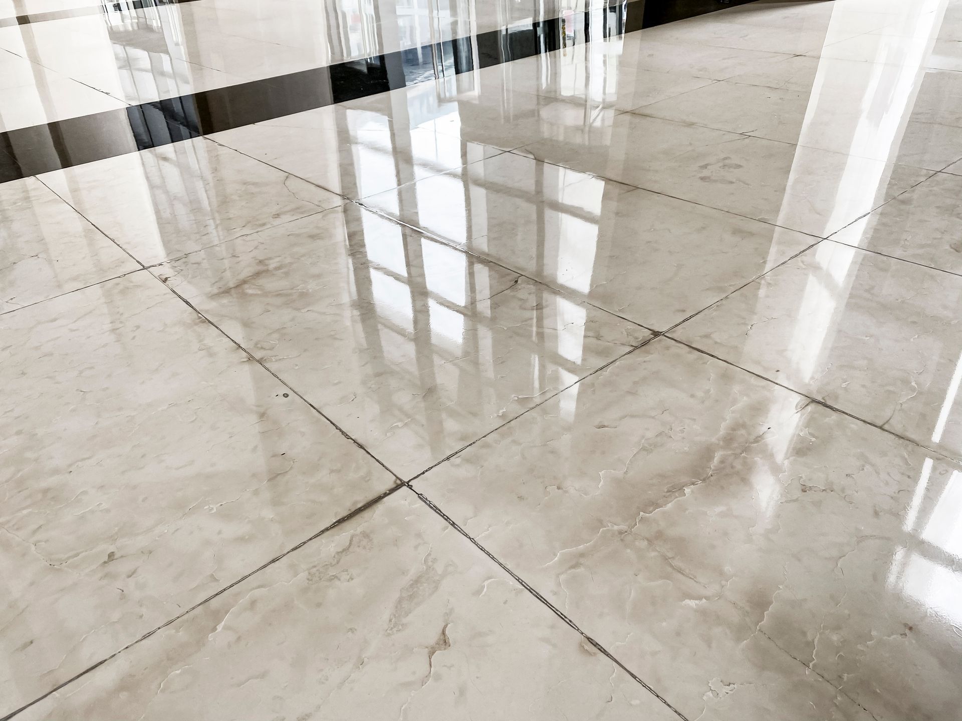A close up of a shiny marble floor with reflections of windows.