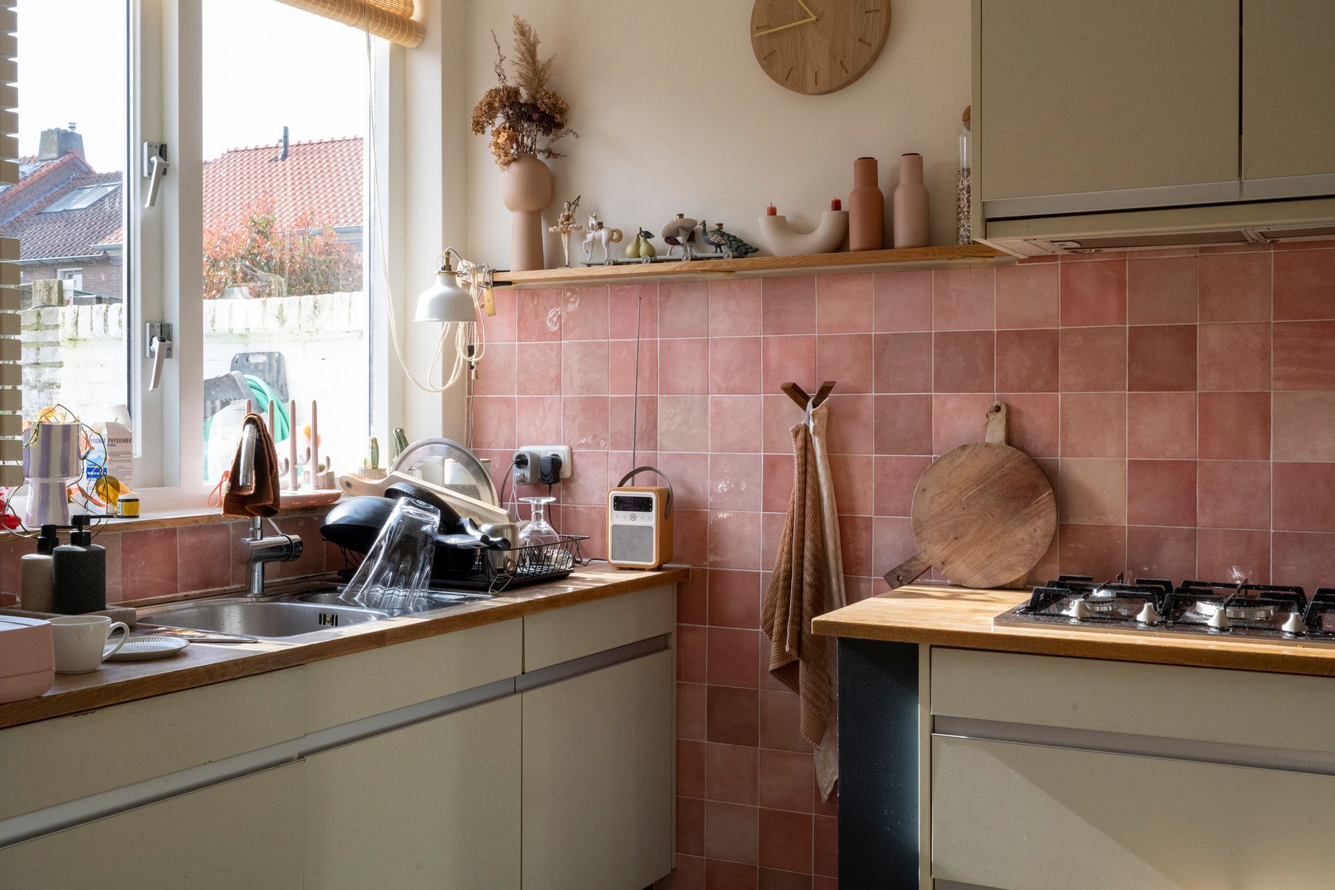 A kitchen with pink tiles and a clock on the wall.