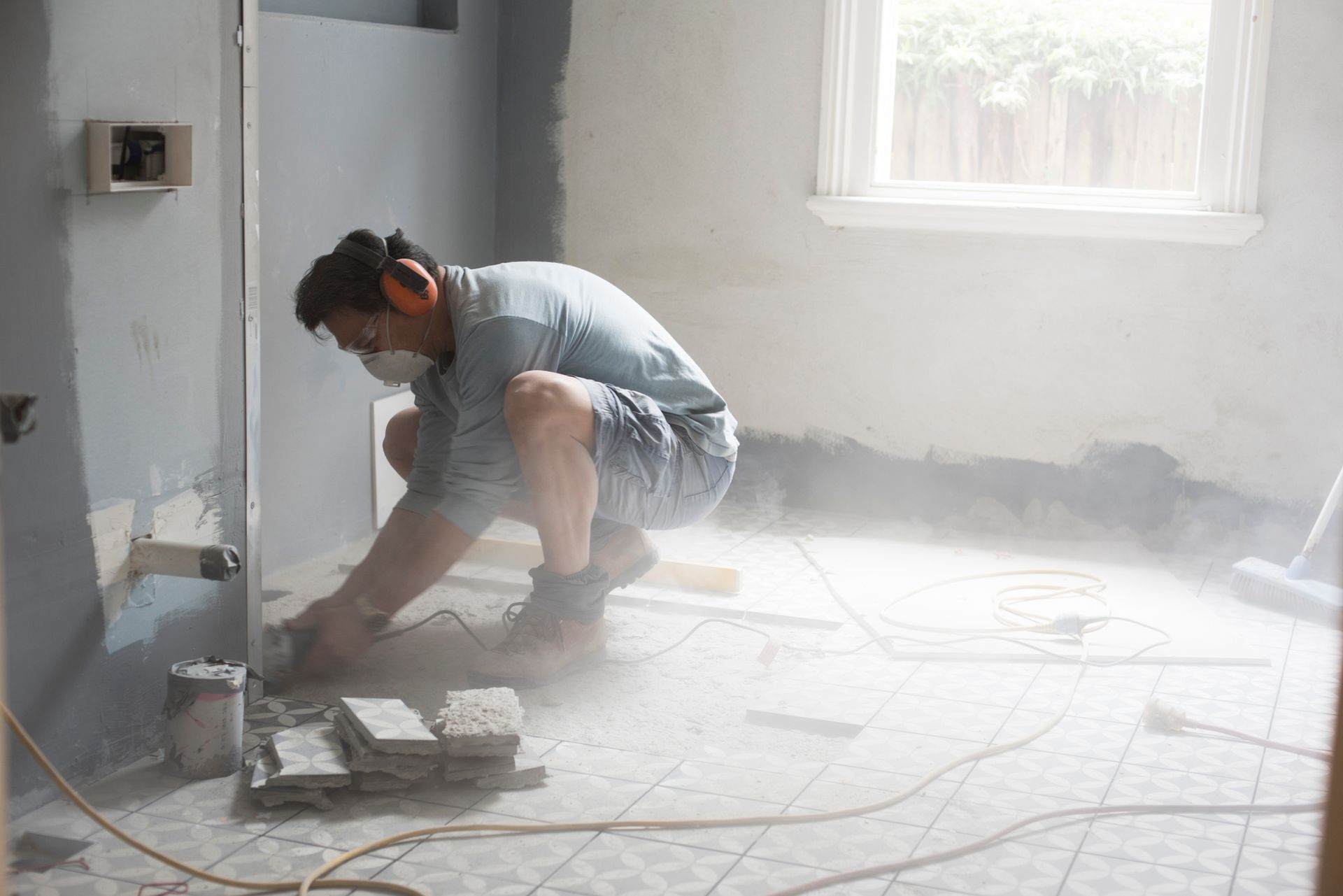 A man is measuring a tile floor with a level.