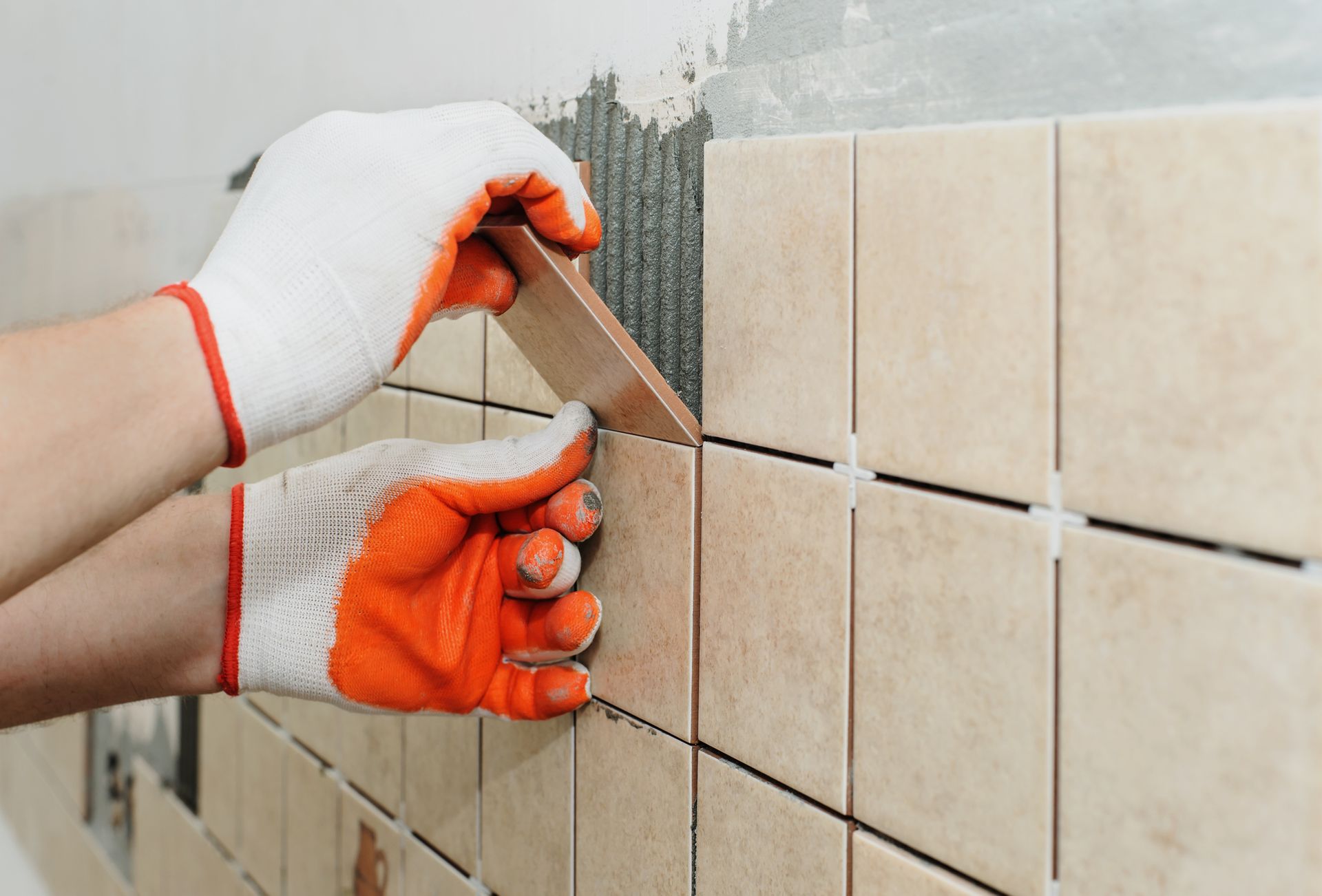 A person is installing tiles on a wall.