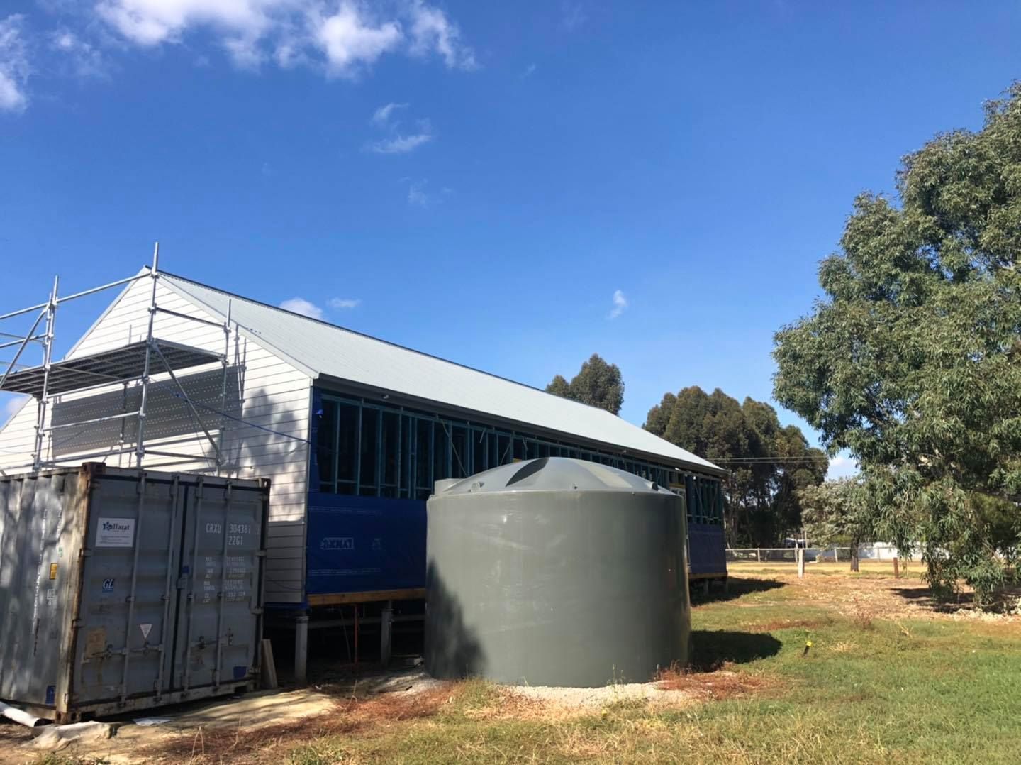 A Large Building With a Water Tank in Front of It — Fig Facility Services in Lara, VIC