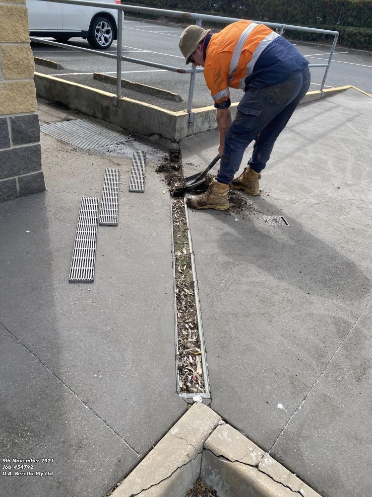 A Man is Working on a Sidewalk With a Shovel — Fig Facility Services in Lara, VIC