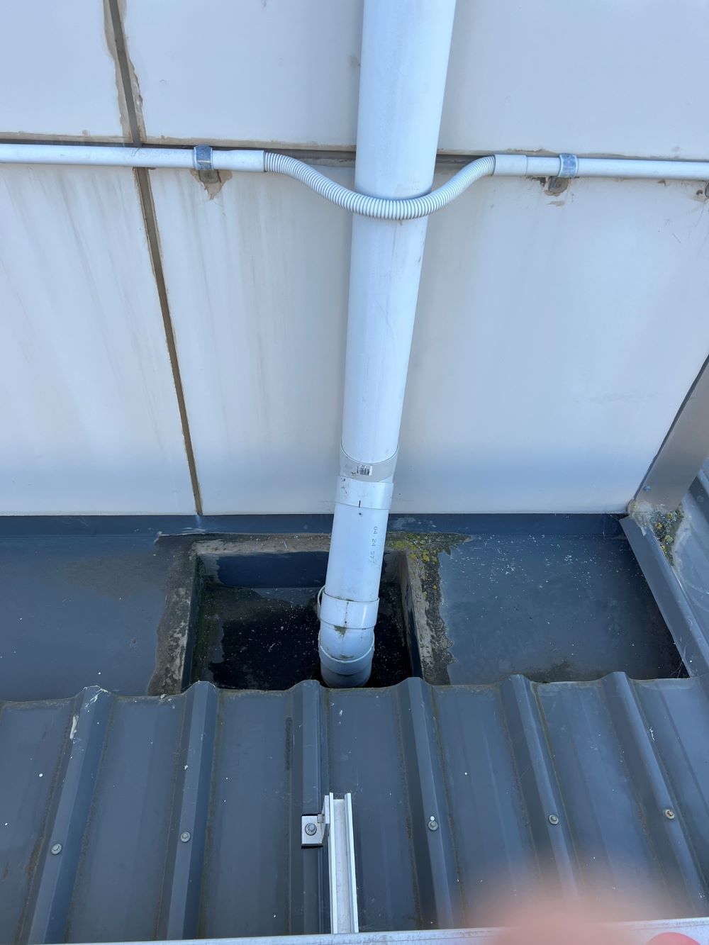 A White Pipe is Coming Out of a Hole in the Roof of a Building — Fig Facility Services in Lara, VIC