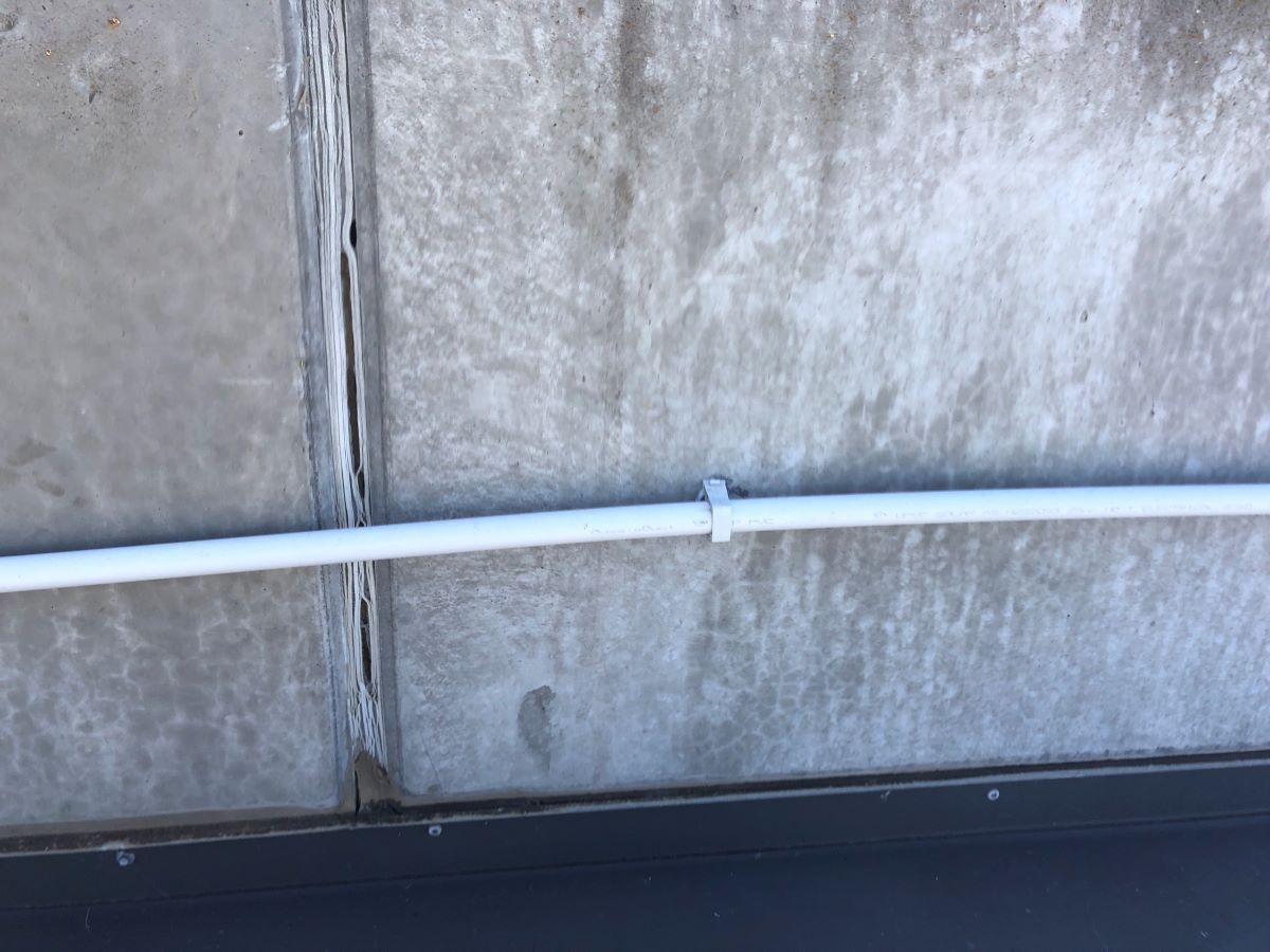 A White Pipe is Attached to a Concrete Wall — Fig Facility Services in Lara, VIC