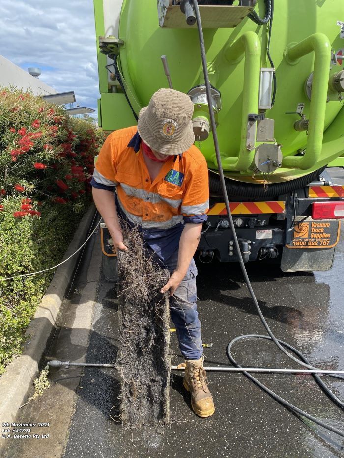 A Man is Standing in Front of a Green Vacuum Truck — Fig Facility Services in Lara, VIC