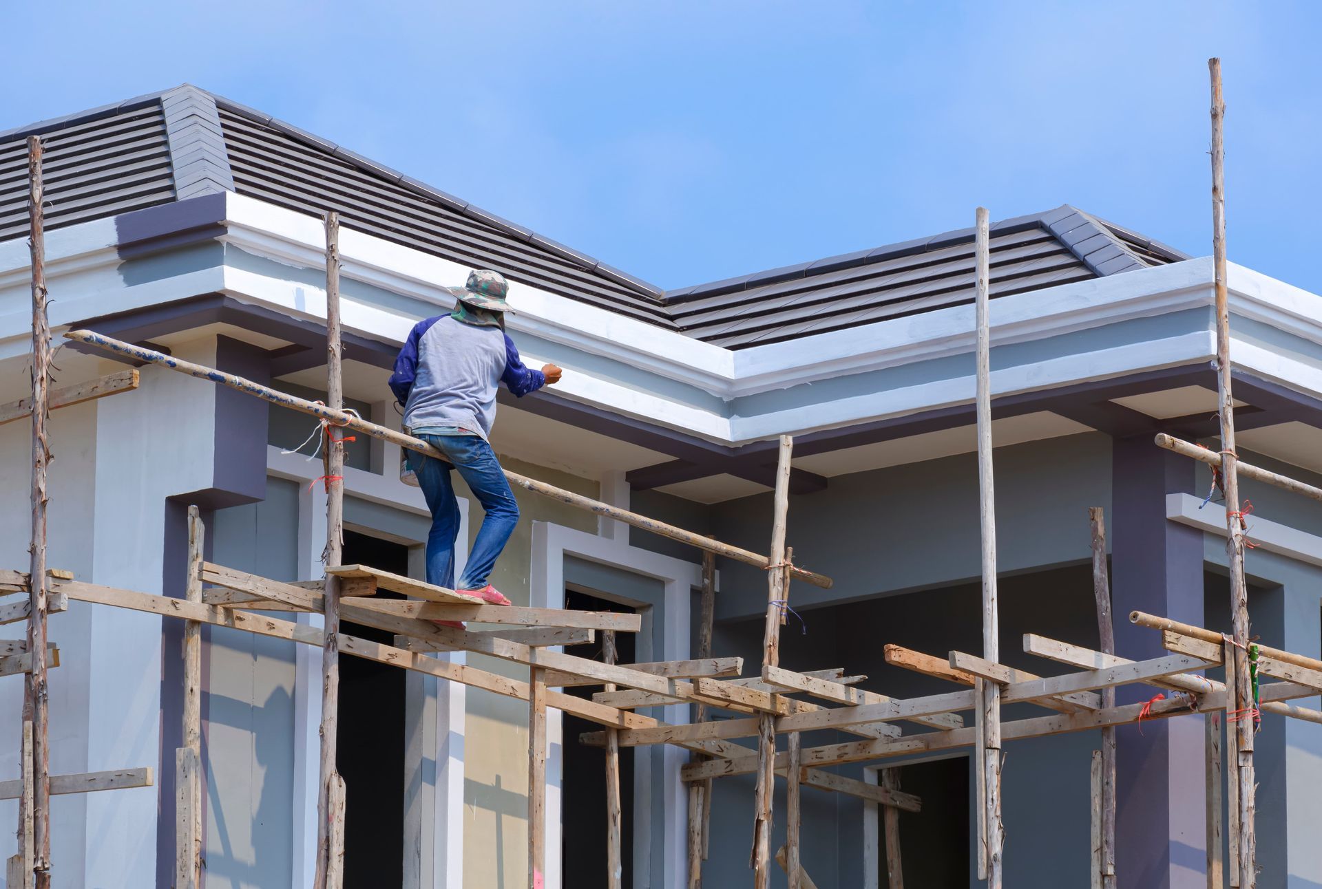 A man is standing on a scaffolding on top of a building under construction.