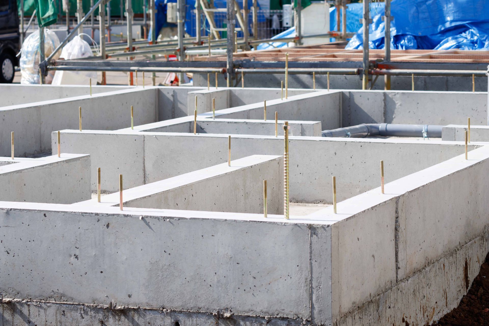 Concrete foundation of a building under construction, with metal rods protruding.