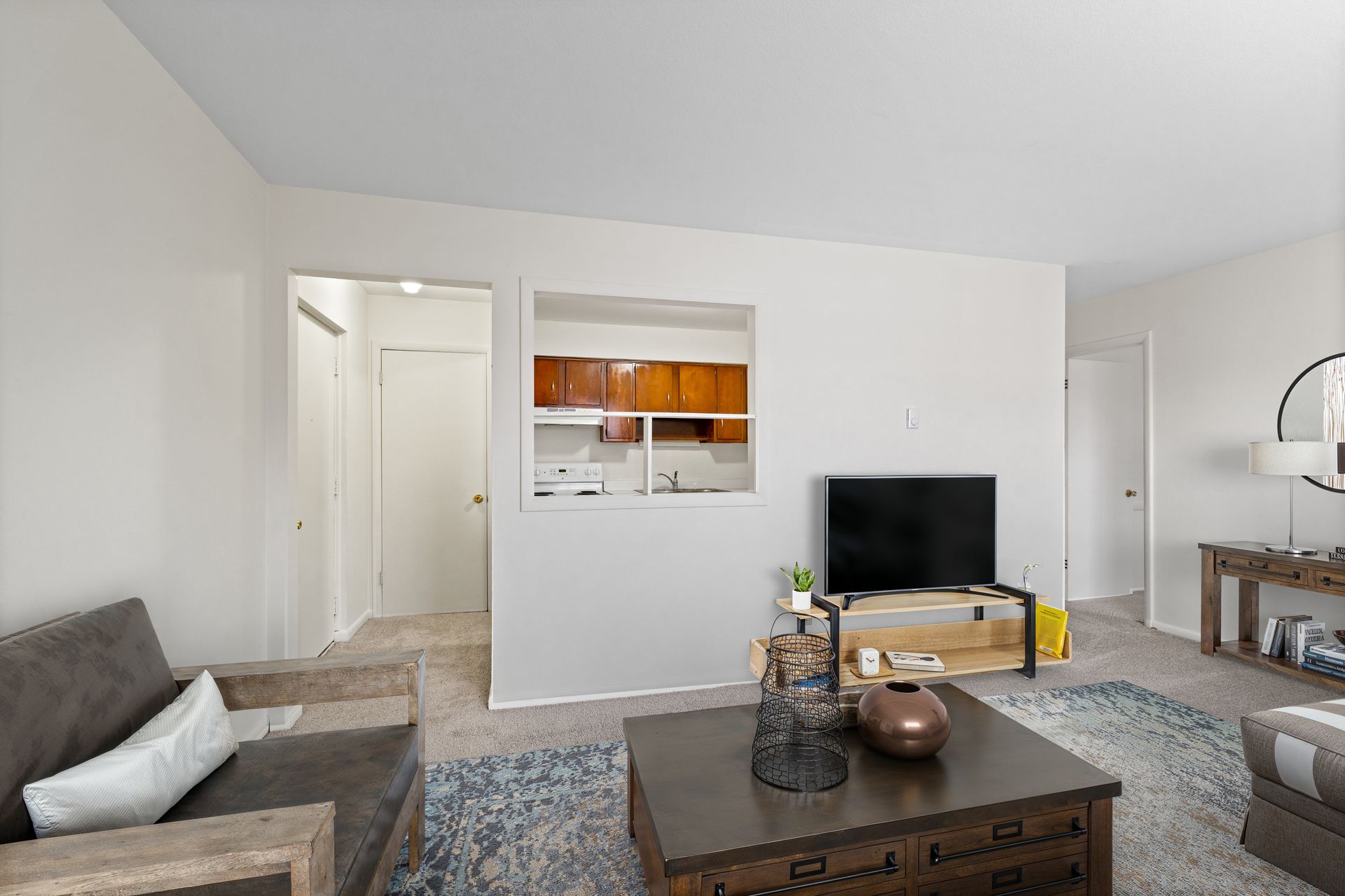 Photo of a living room with the kitchen in the background