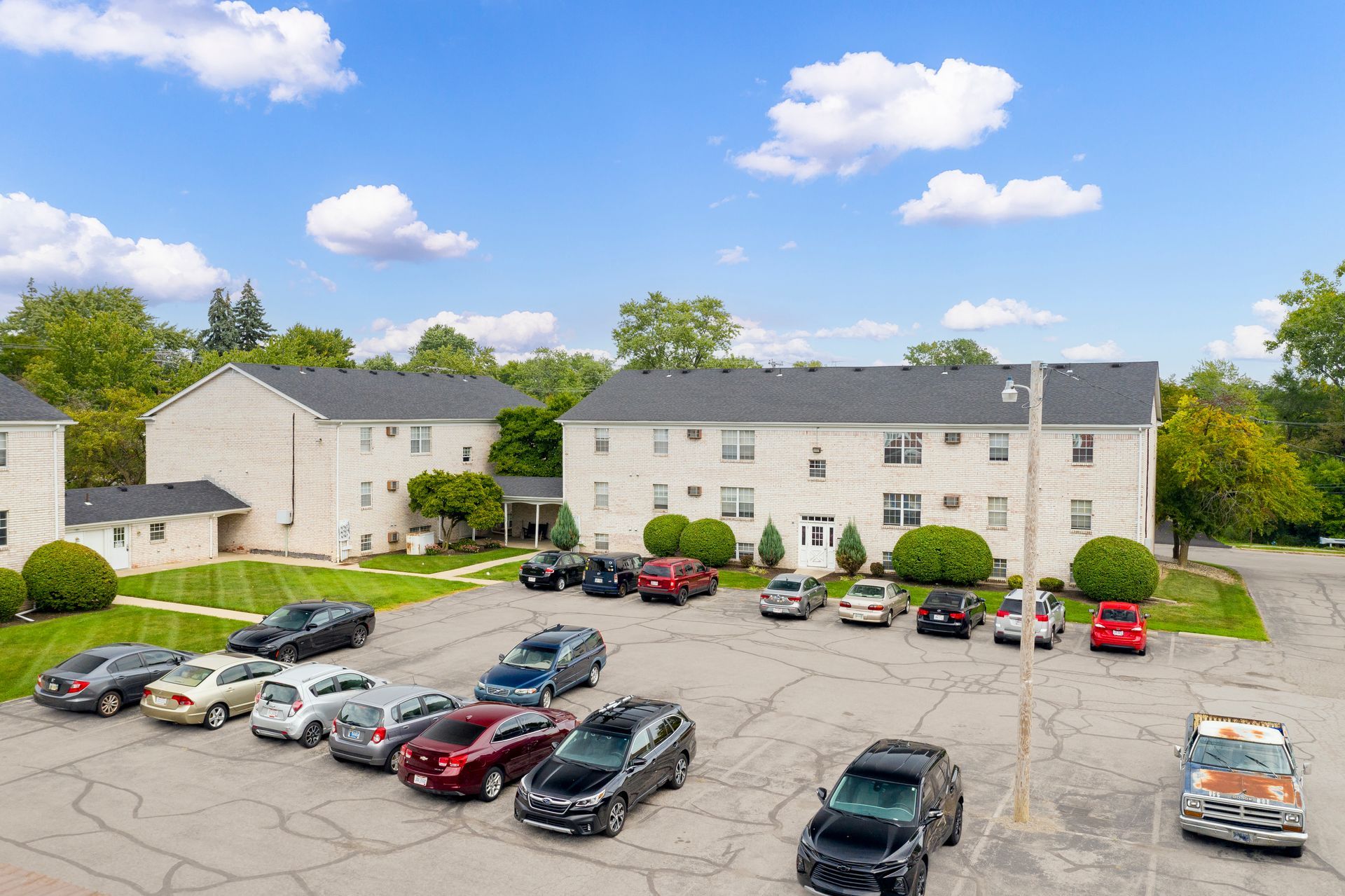 Photo of the community parking lot with buildings in the background and a partially cloudy sky