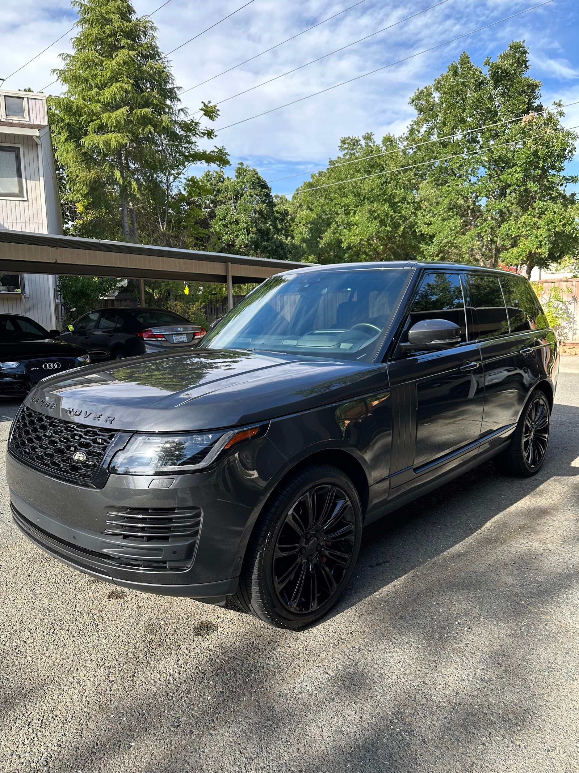 A black range rover is parked in a gravel lot.