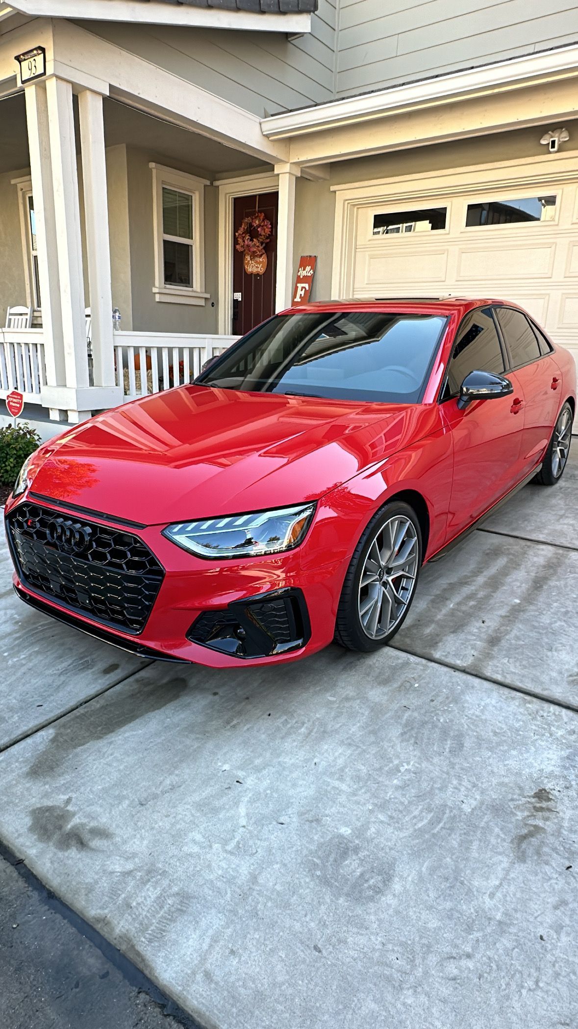 A red car is parked in front of a house.