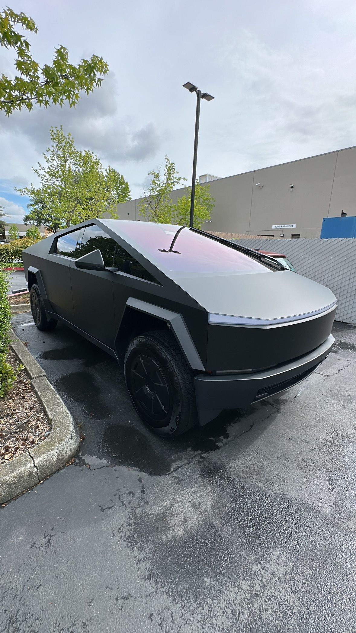 A black tesla cybertruck is parked in a parking lot.
