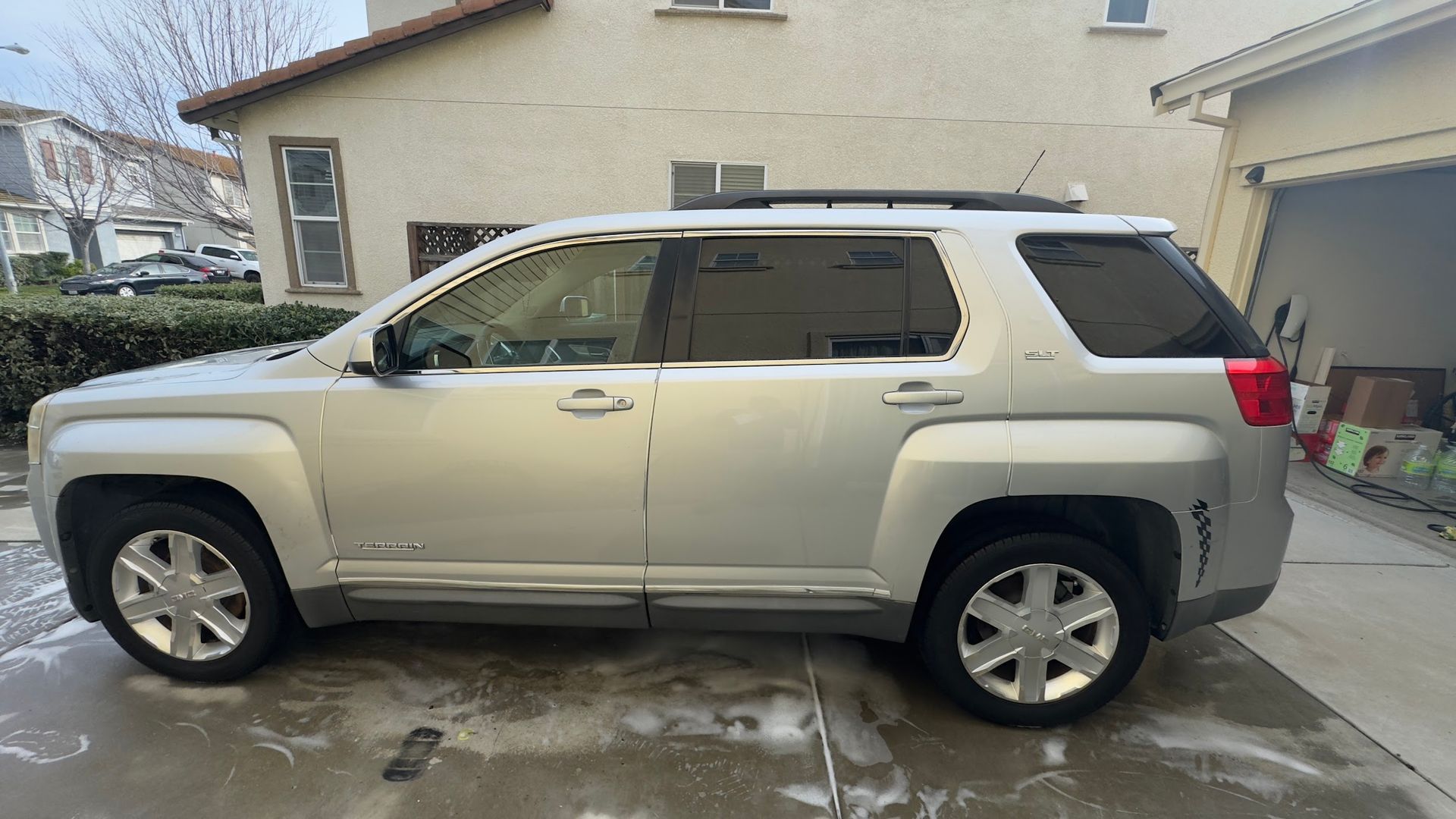 A silver suv is parked in a driveway in front of a house.