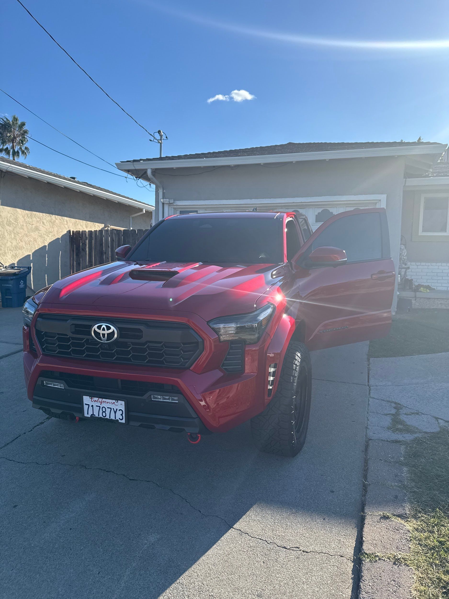 A red truck is parked in front of a house with its doors open.