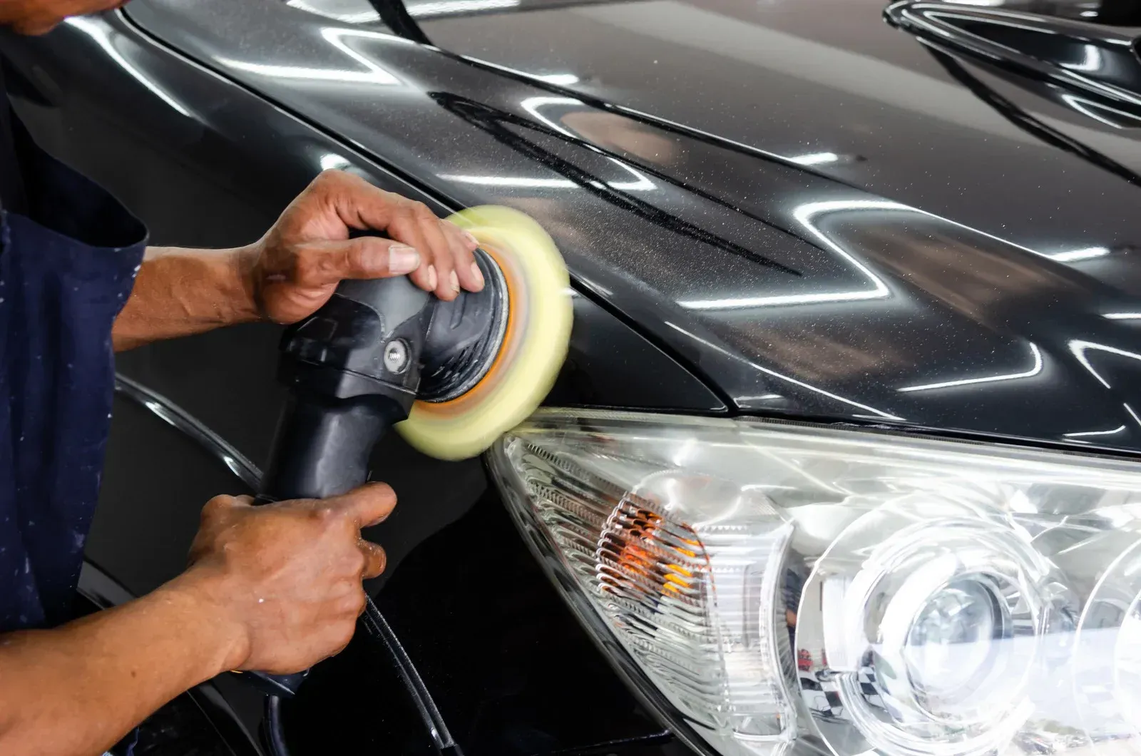 A man is polishing a car with a machine.