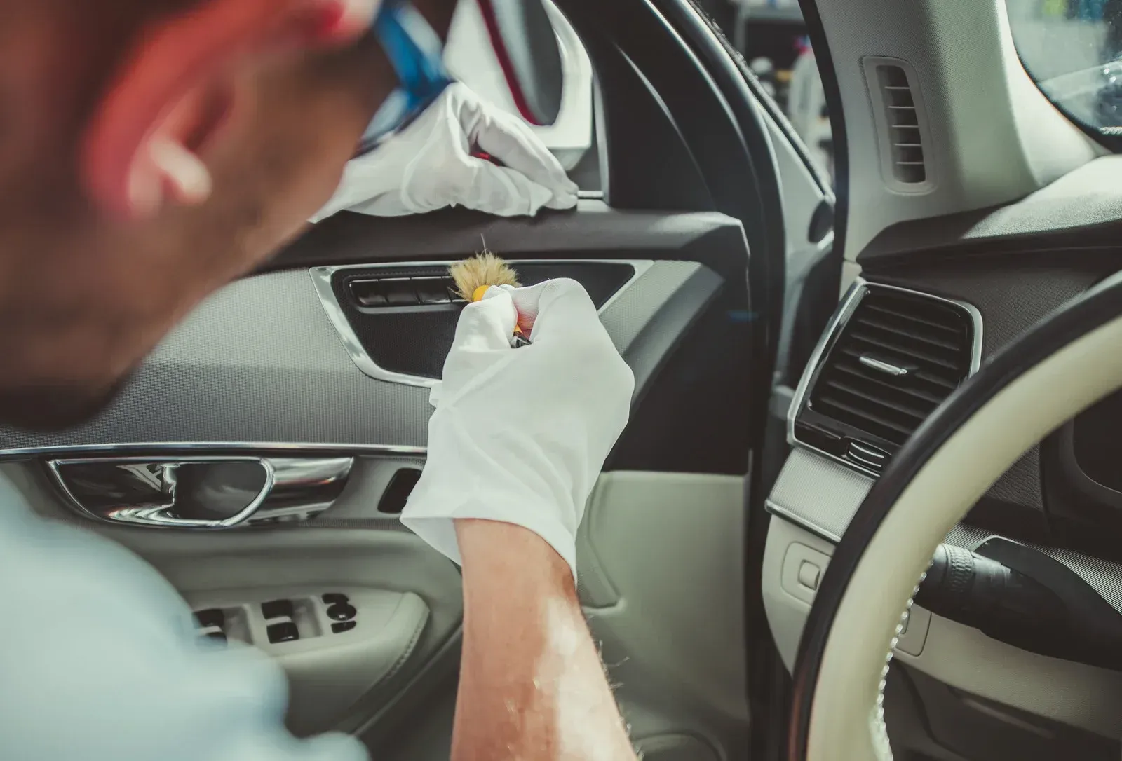 A man is cleaning the interior of a car.